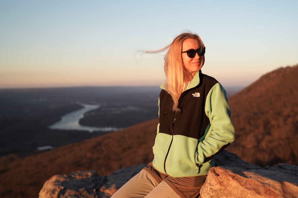 A woman wearing the Retro Denali fleece jacket at sunset