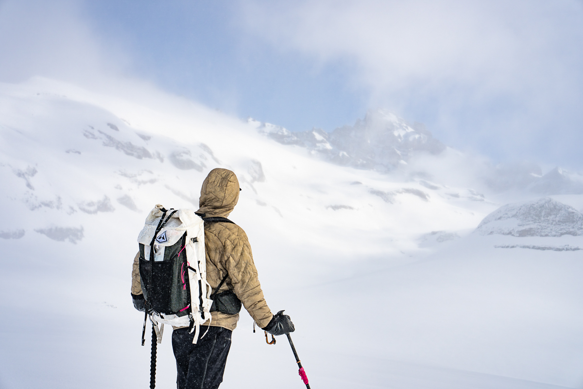 A skiier admired a misty, snow-covered mountain in the distance.