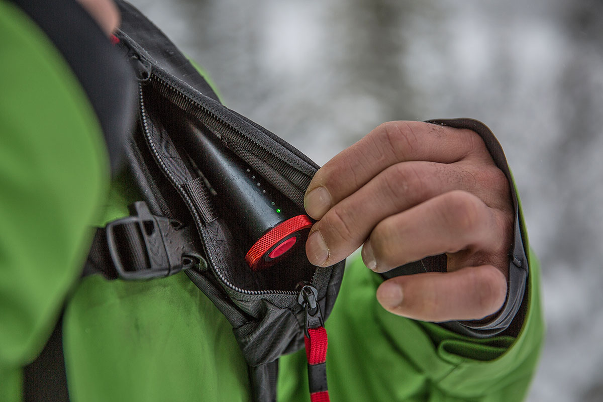 A person showing the trigger of an avalanche airbag backpack