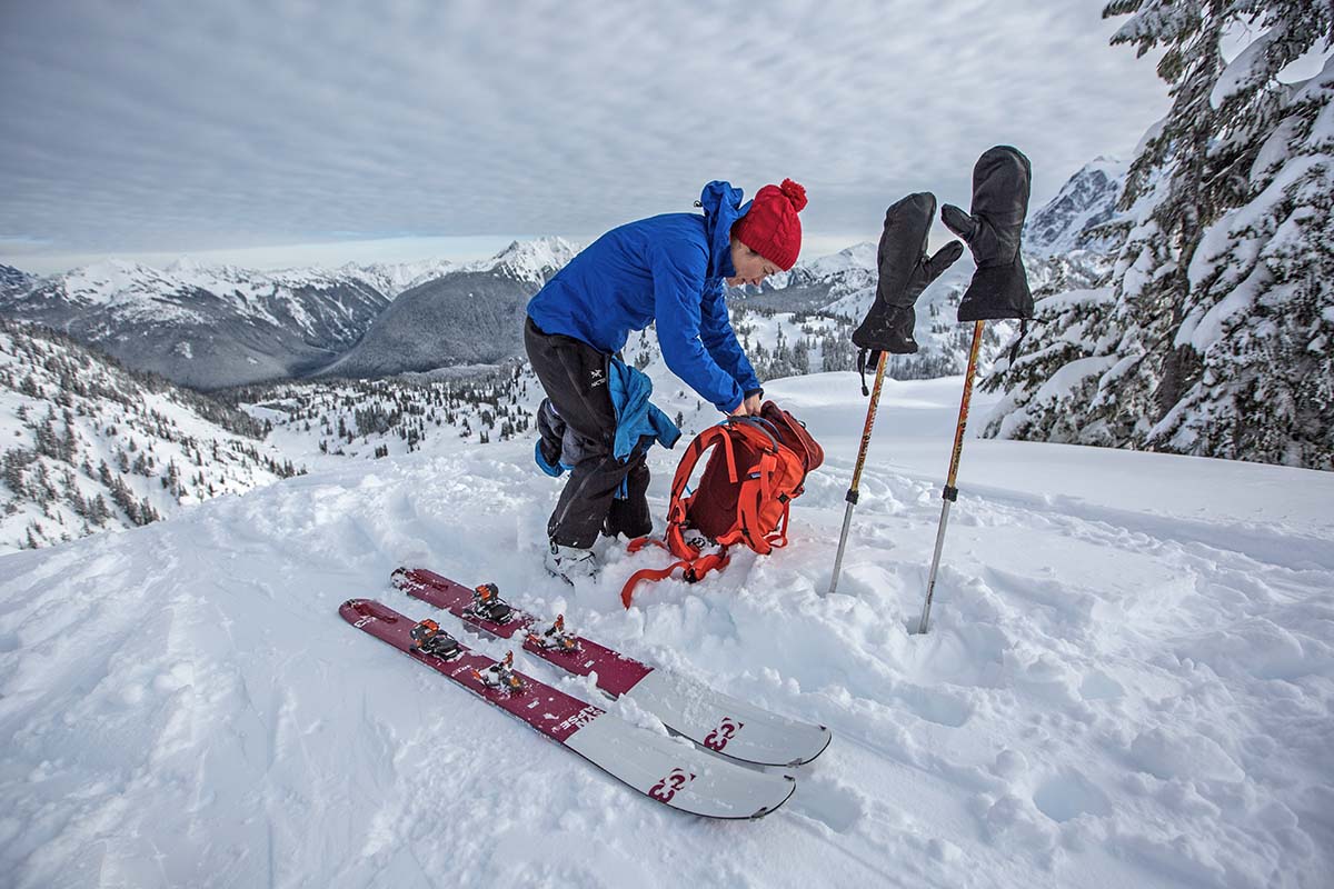 A skier at the top of a mountain, inspecting their gear before they descend