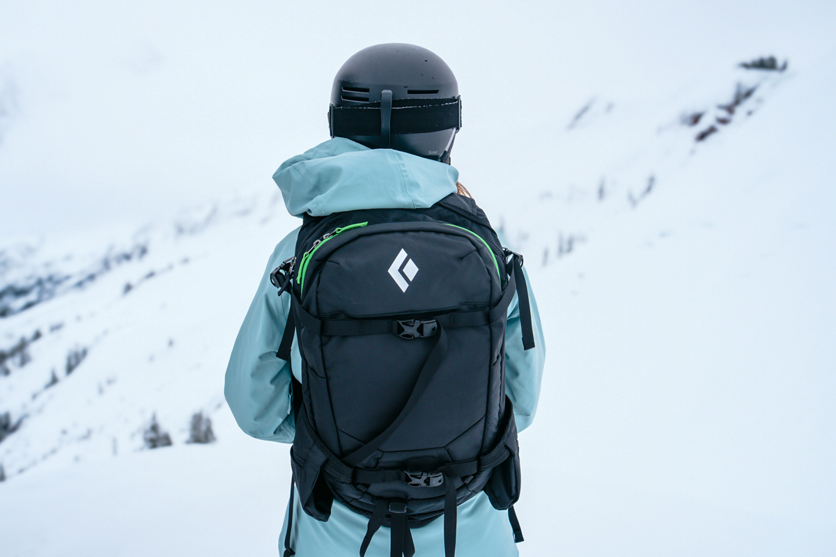 A woman gazing out into the mountains with a Black Diamond ski backpack on. 