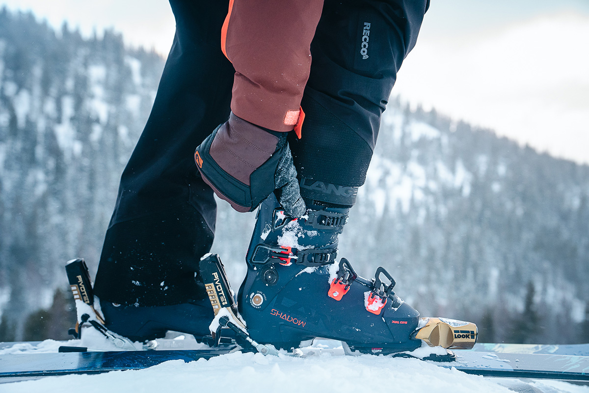 A skier adjusting their boot with Look Pivot bindings on their skis