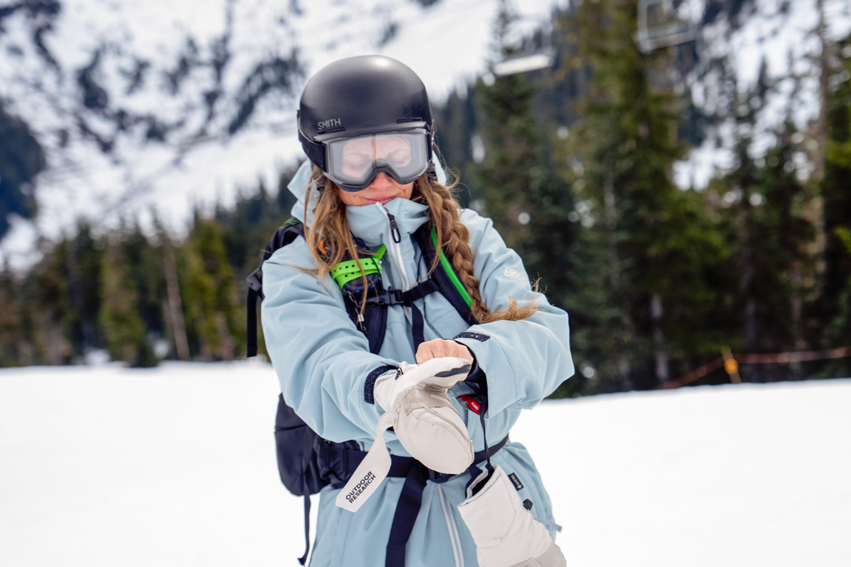 A woman pulling on white ski gloves