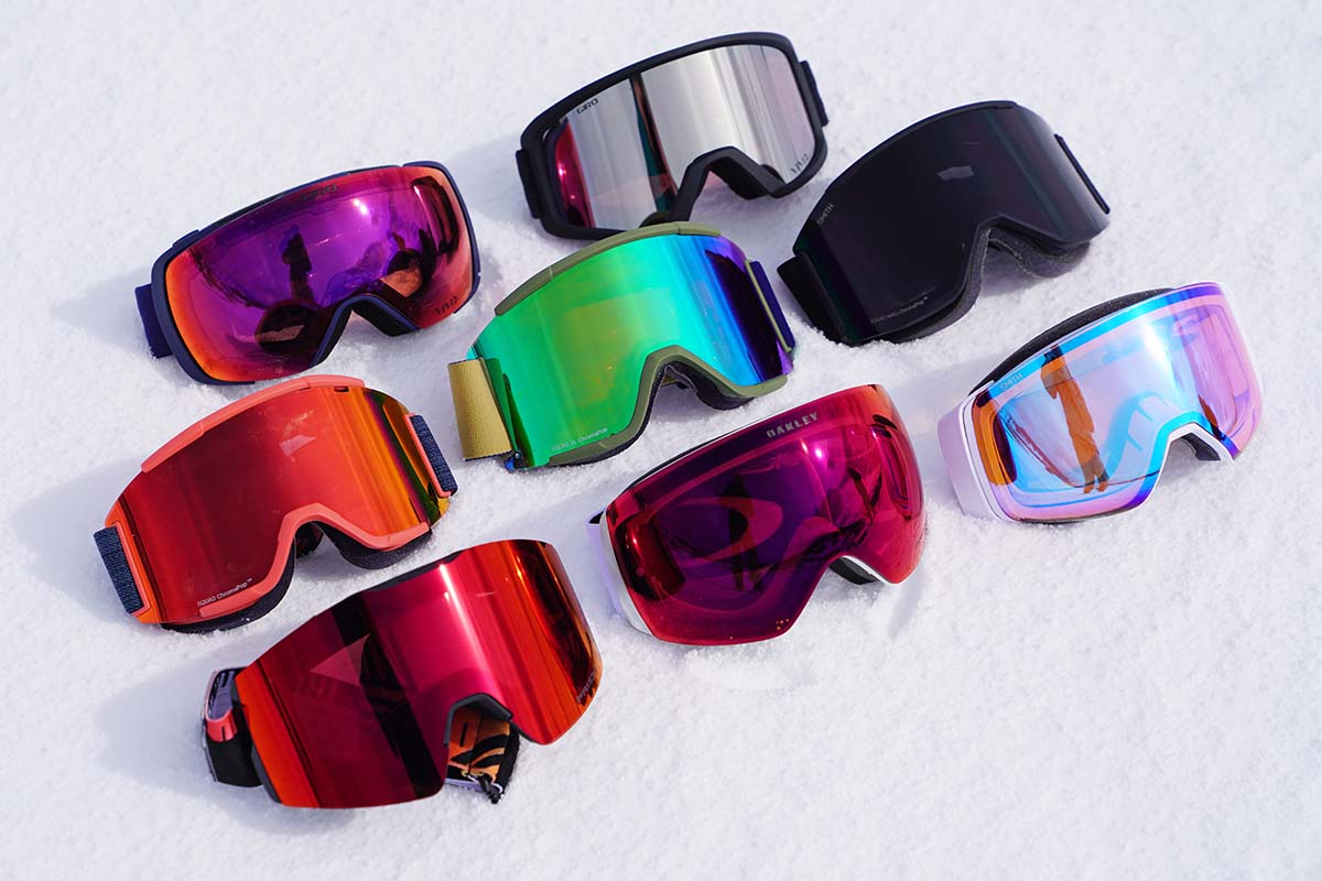 A full lineup of Smith and Oakley goggles set out in the snow