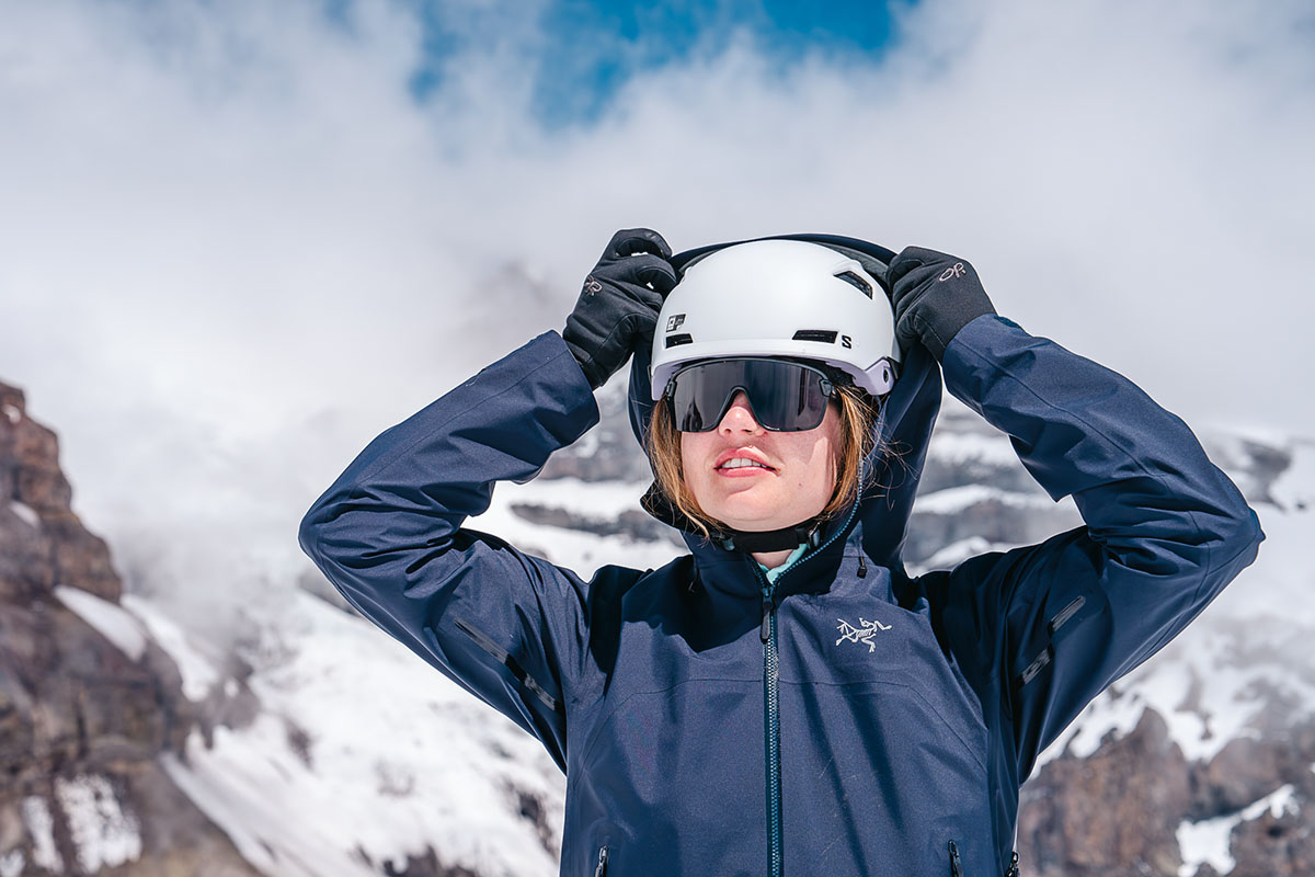 A woman pulling a hood over a ski helmet