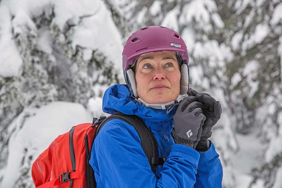 A woman buckling her ski helmet.