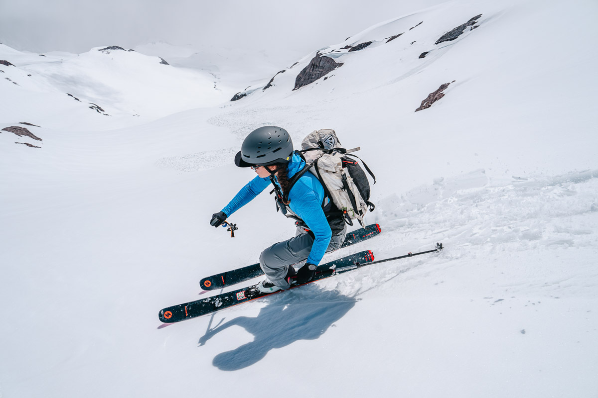 A woman skiing down mountain wearing grey ski helmet