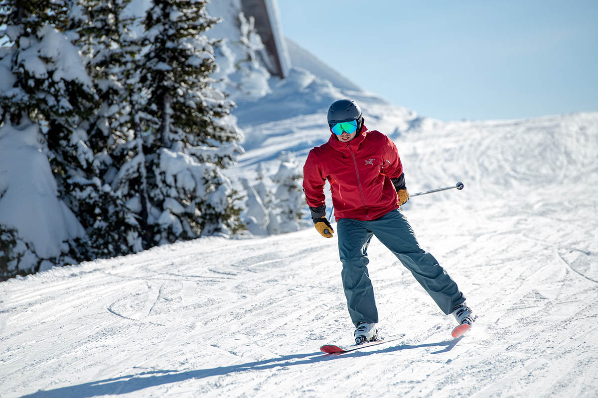A man in a red jacket skis down a groomer at the resort