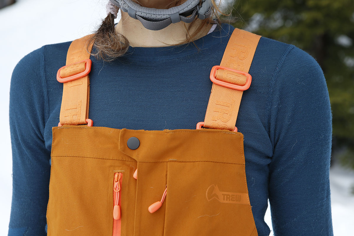 A close-up of the Trew Gear Logo on a pair of orange bibs