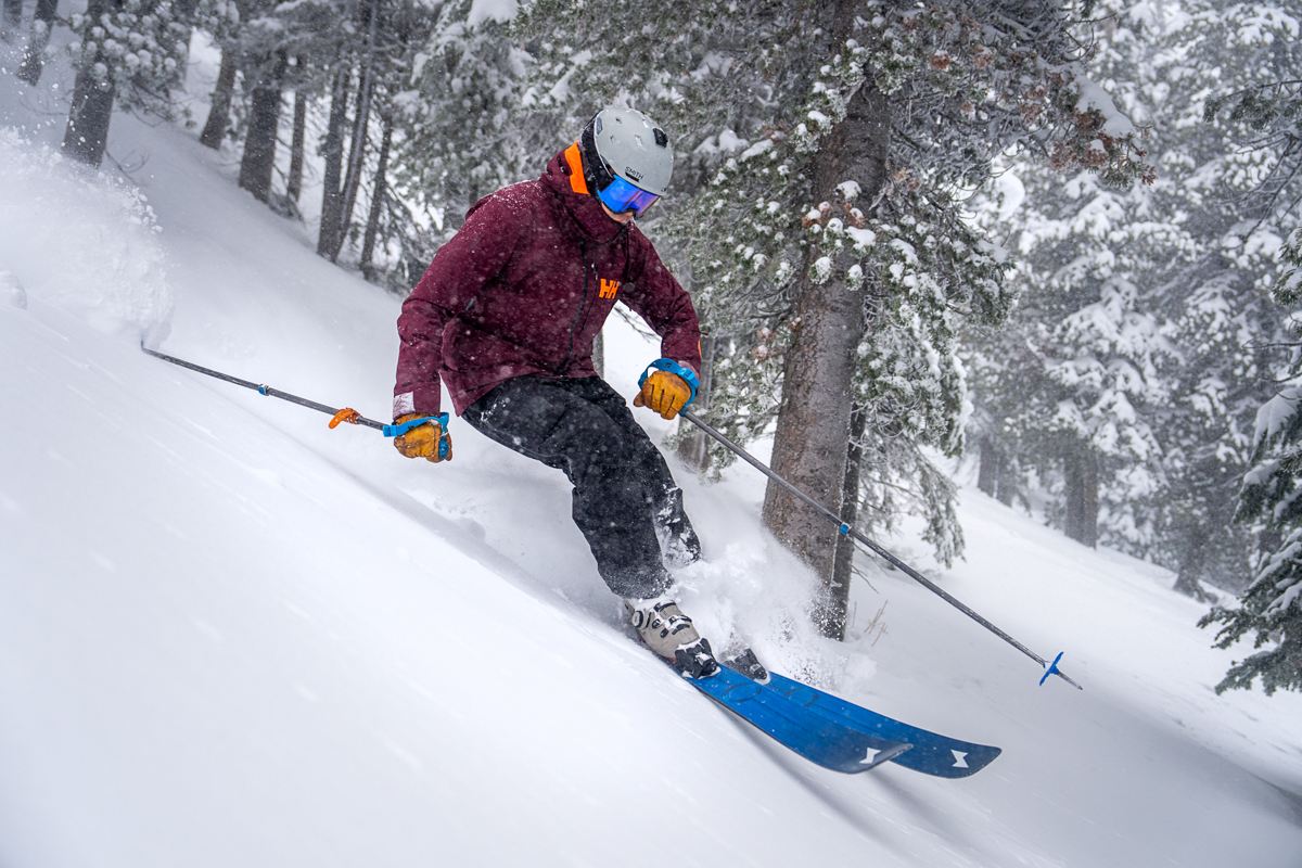 A skier goes quickly downhill in powder while surrounded by trees
