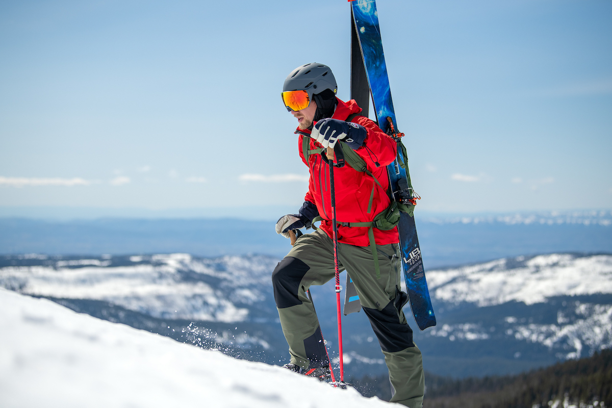 A man boot packs up a hill with his skis A-framed on his back
