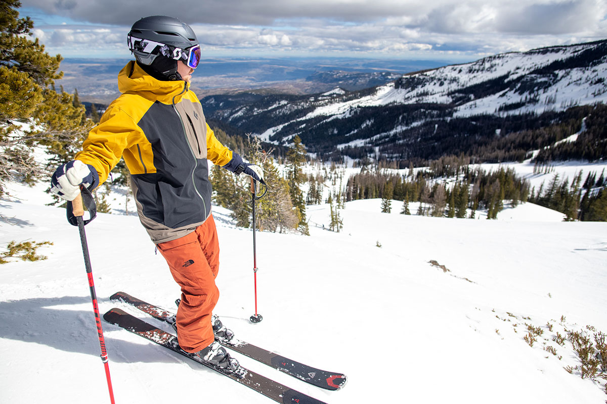 A man stands above a ski run while wearing The North Face Freedom pants