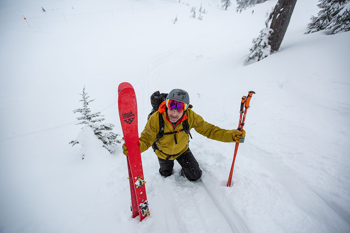 A man bootpacking up a steep snowy slope with ski poles
