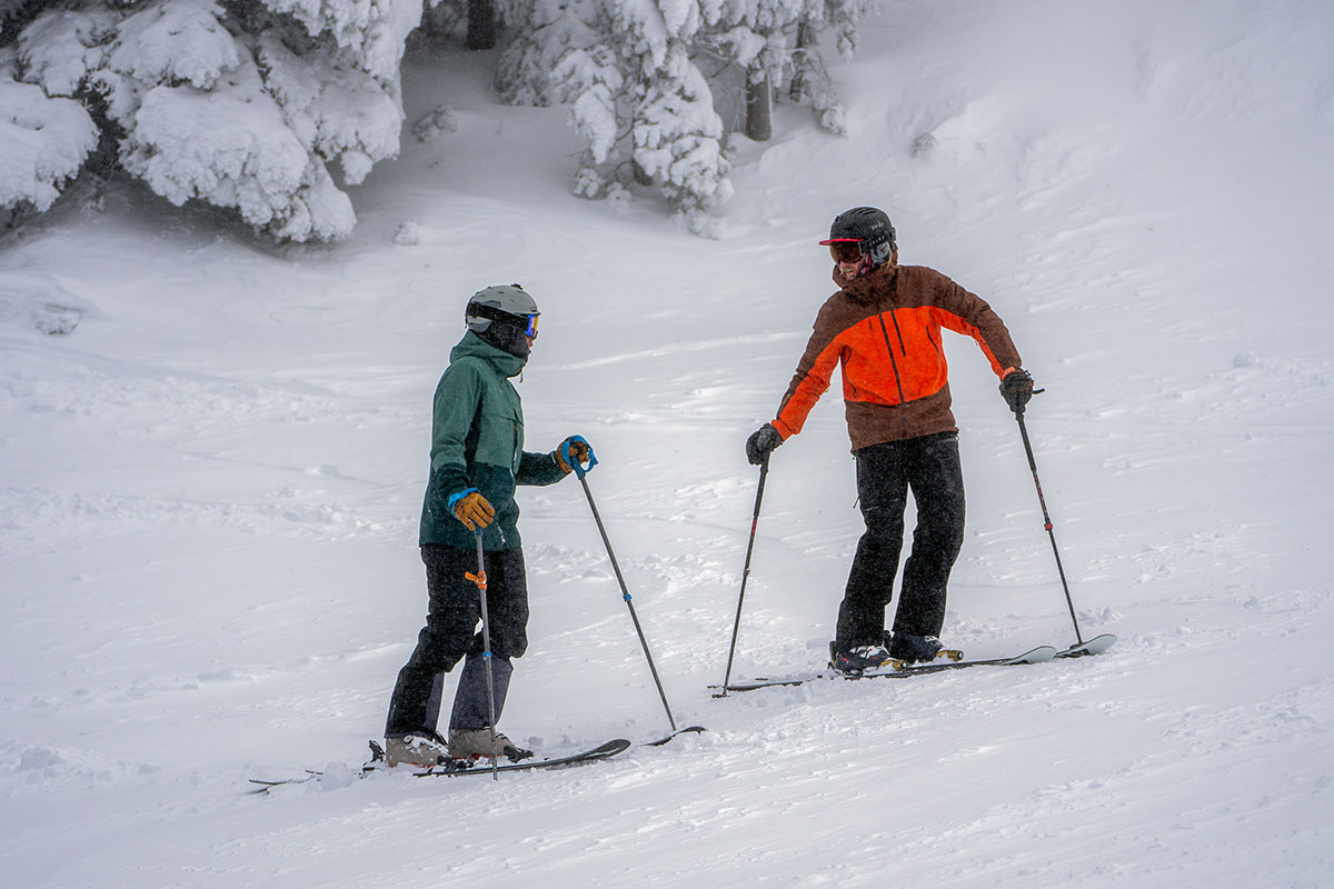 Two skiers talking while holding ski poles