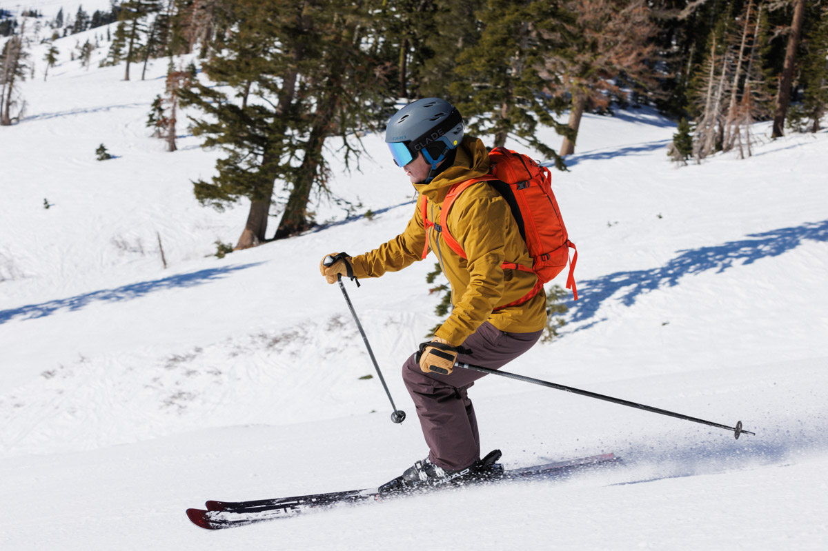 A man skiing down a ski run with ski poles