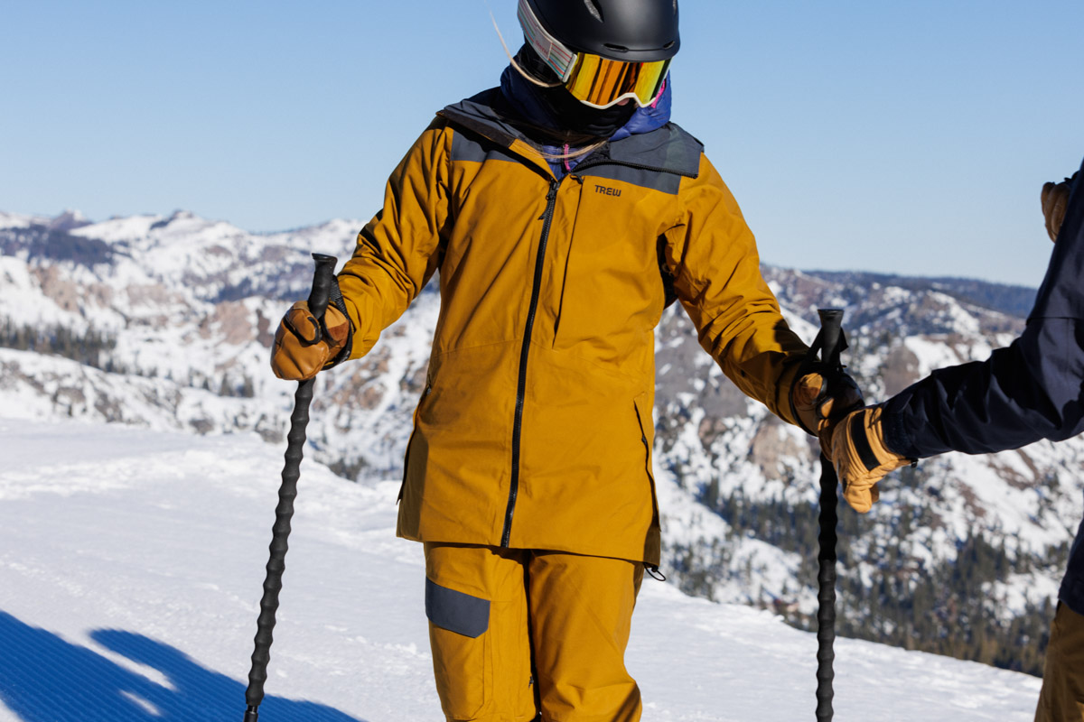 A skier stands at the top of a run with poles in hand
