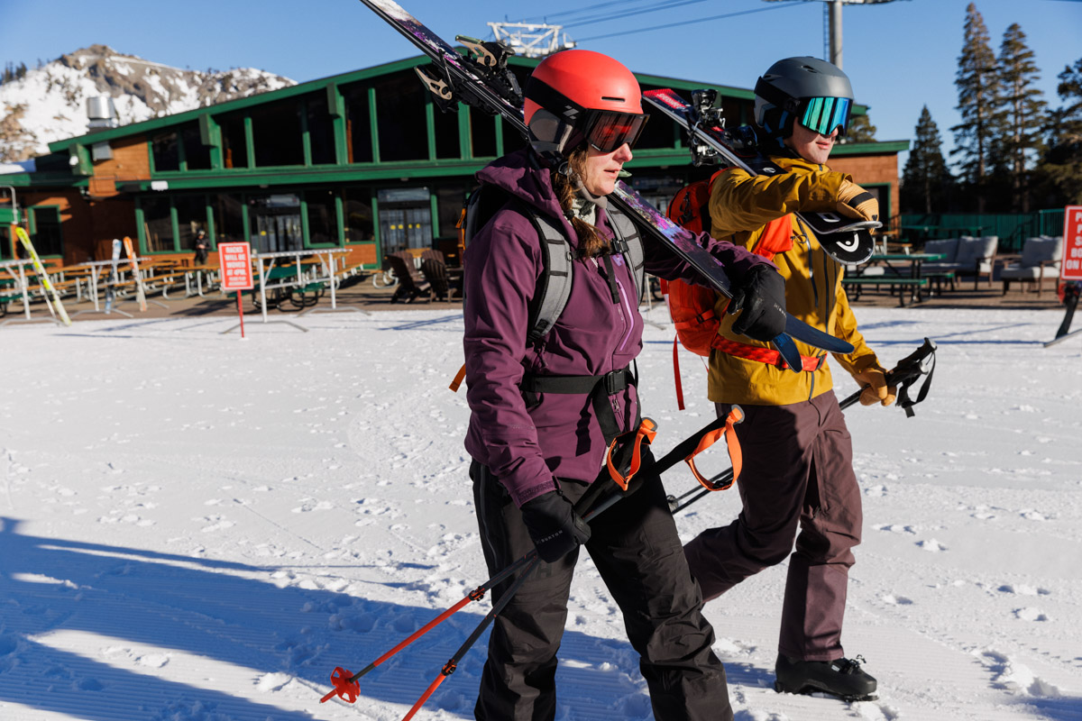 Two skiers carrying their skis and ski poles