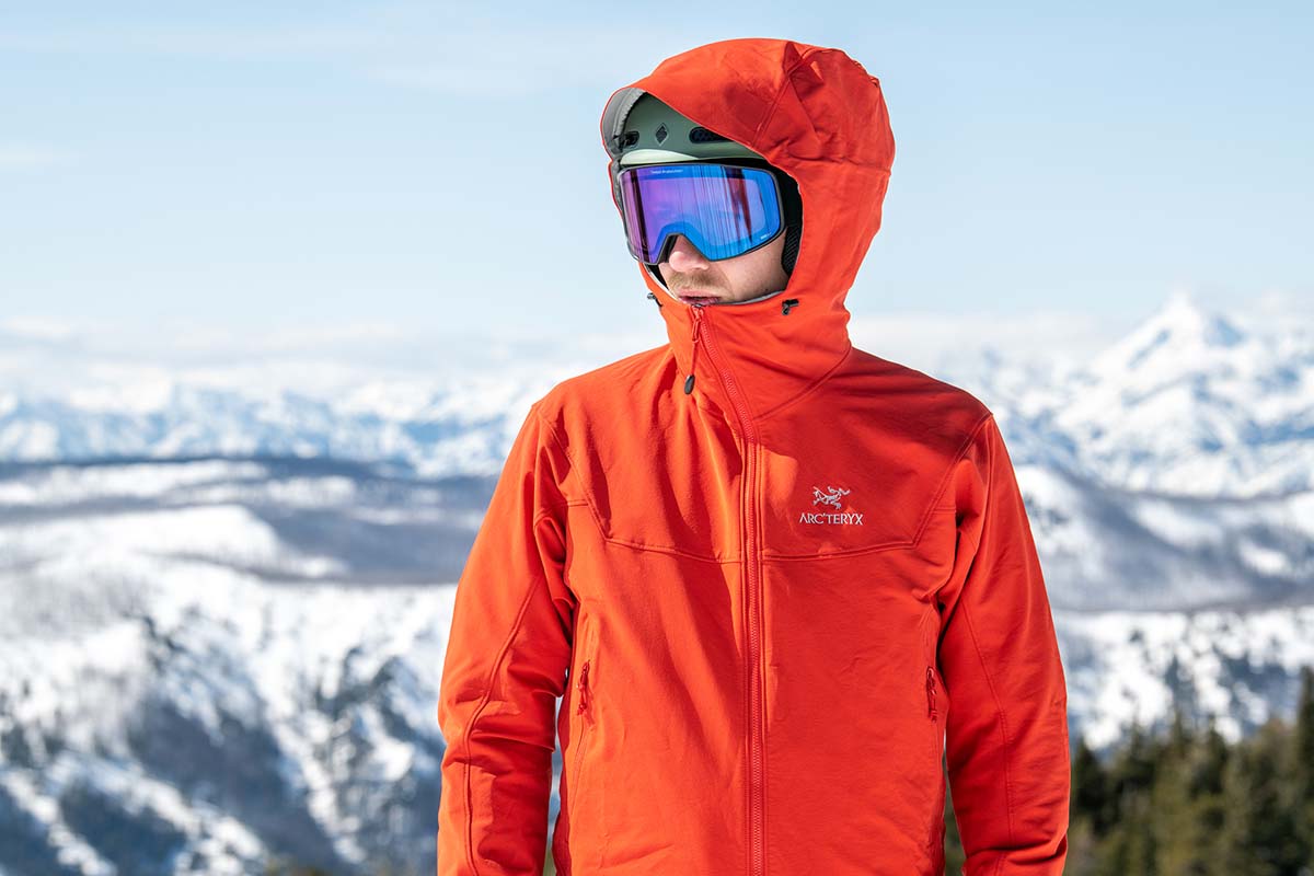 a man with his hood up and ski goggles is standing on the mountain