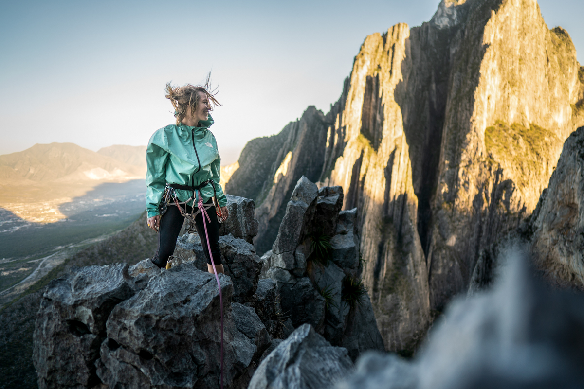 a climber stands on the rocks and smiles off to the right