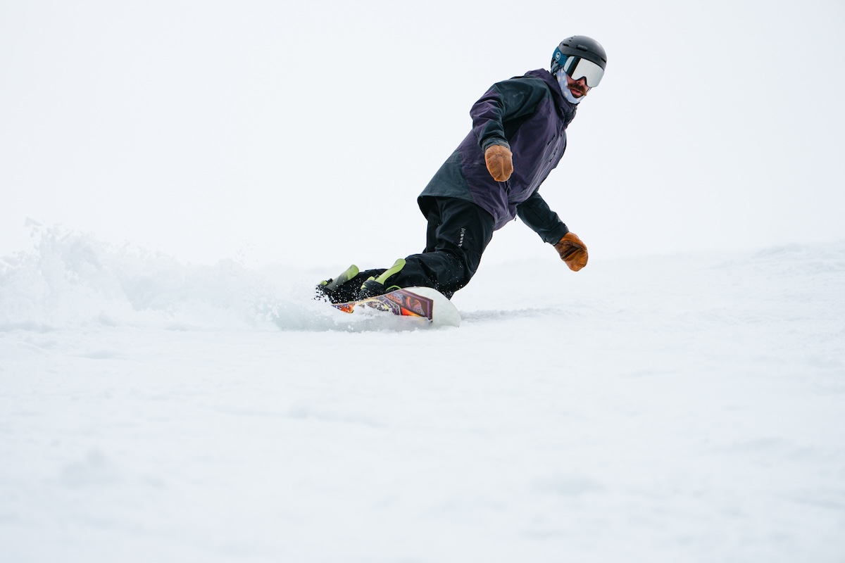 A snowboarder carving down the run using Jones Mercury FASE bindings
