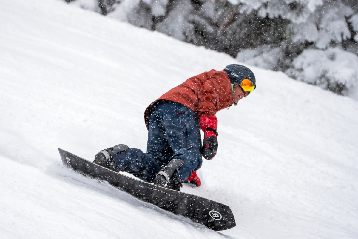 A snowboarder rides down a snowy mountain. 