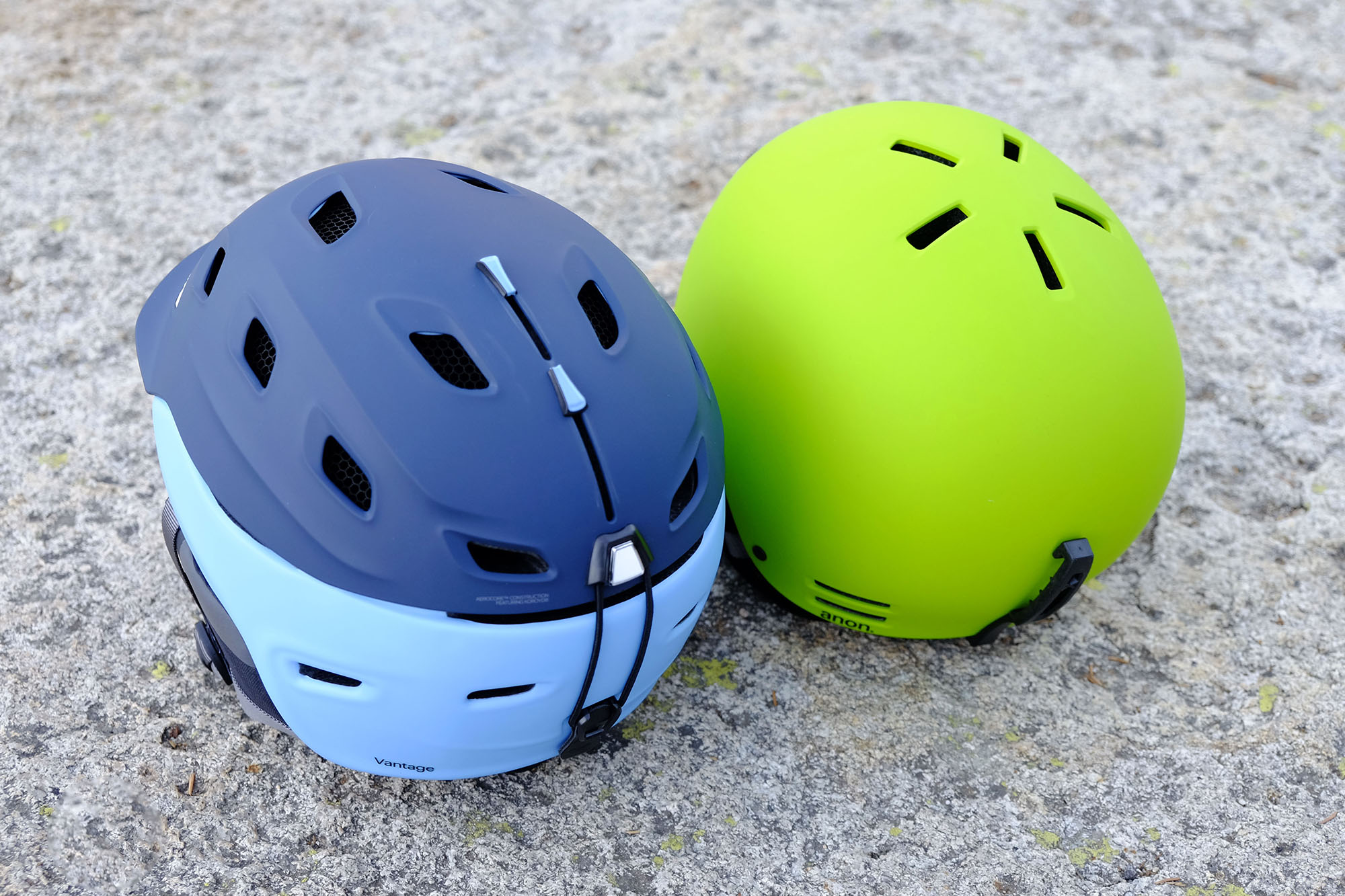 Two helmets are side-by-side on the ground to compare the number of vents.