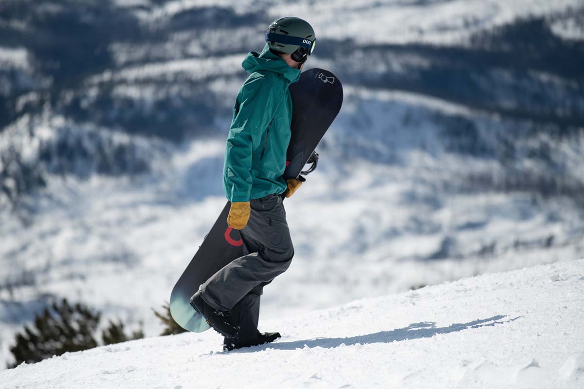 A snowboarder carrying a board in the mountains