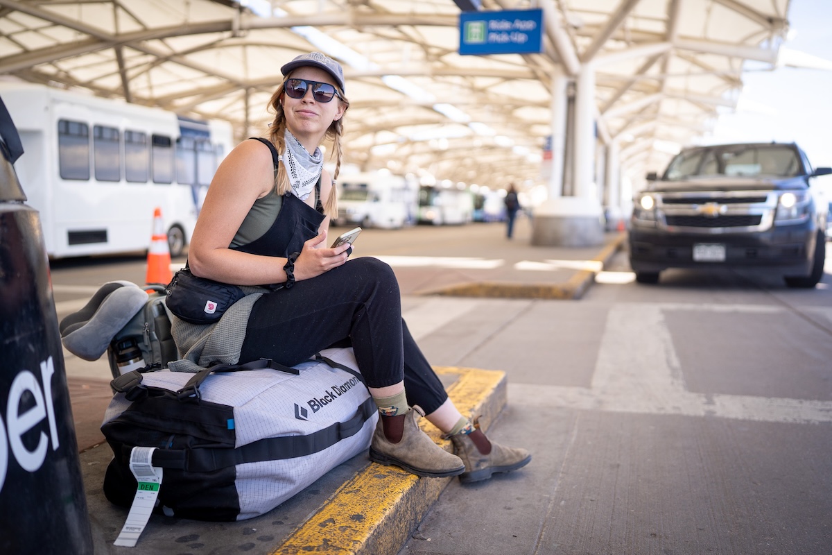 sitting at the airport on a duffel bag wearing travel pants 