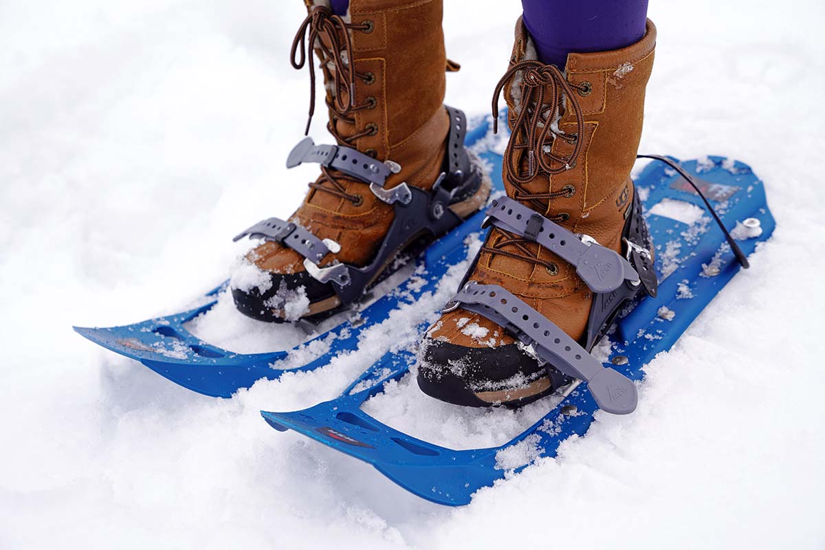 A pair of boots strapped to blue snowshoes