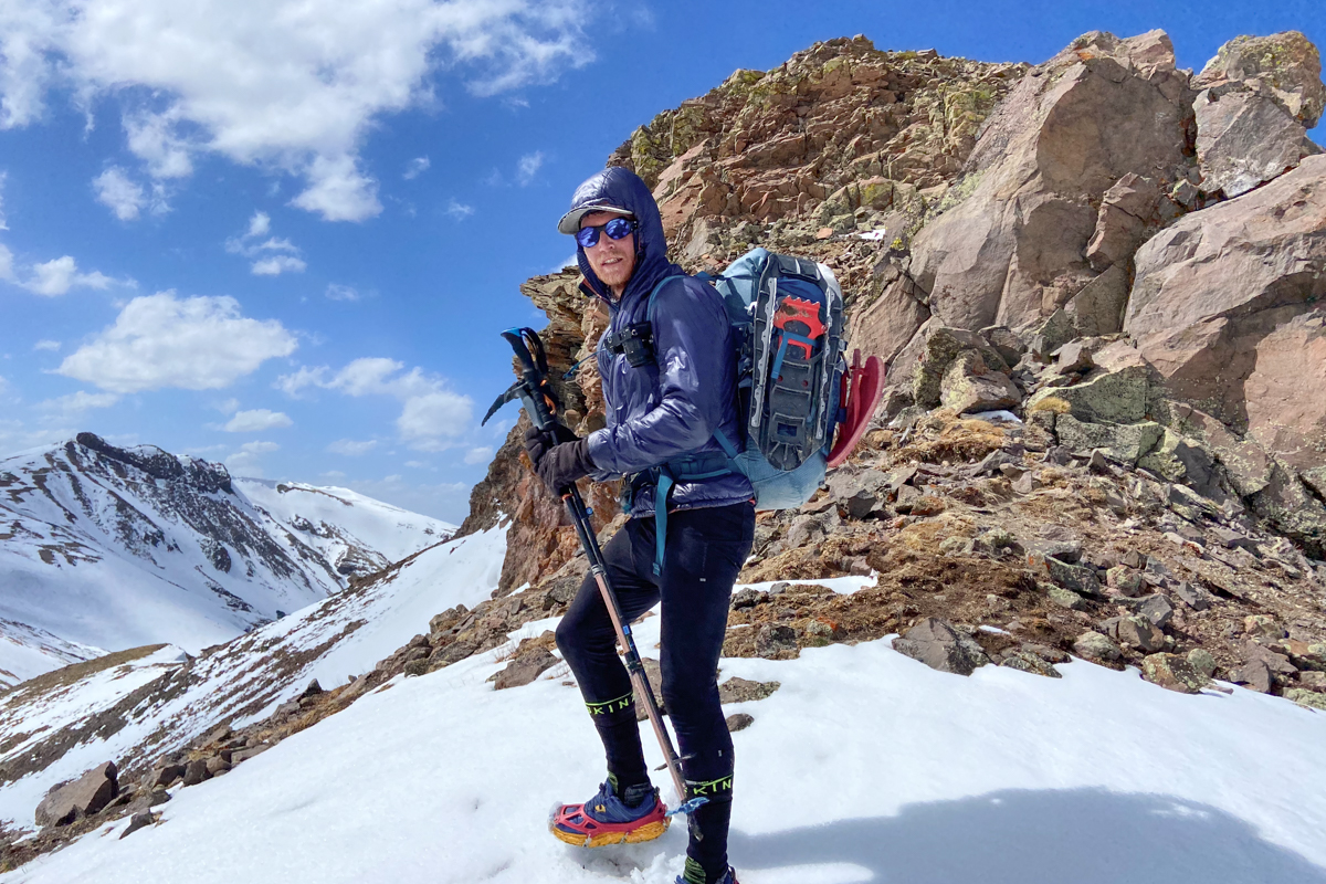 A man on the top of ridge with snowshoes strapped to his pack