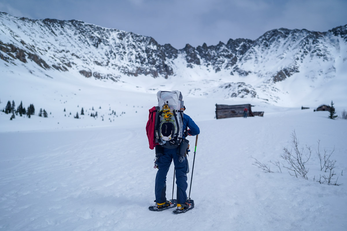 A man standing in the mountains with snowshoes