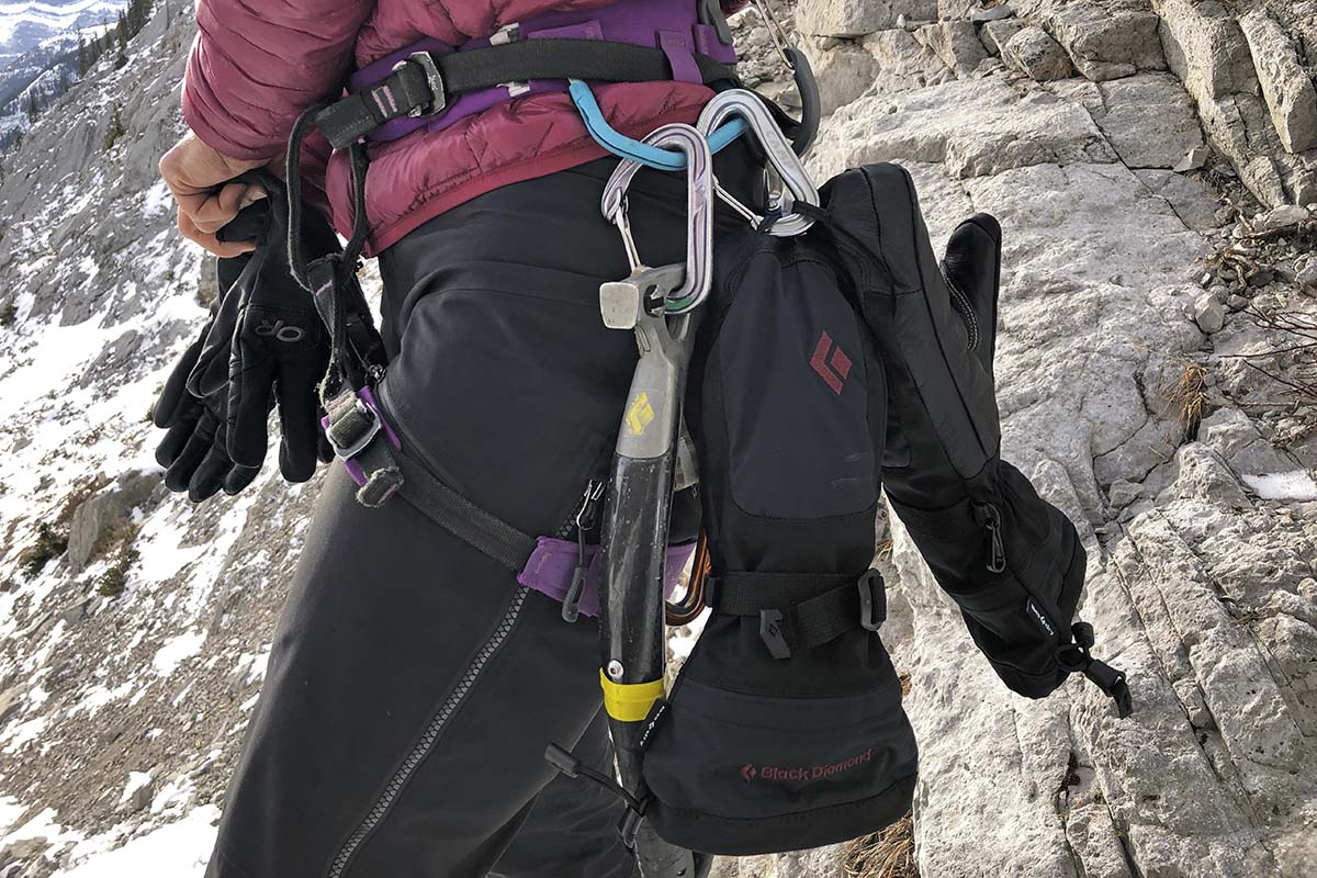 A pair of winter mittens hanging off a climbing harness