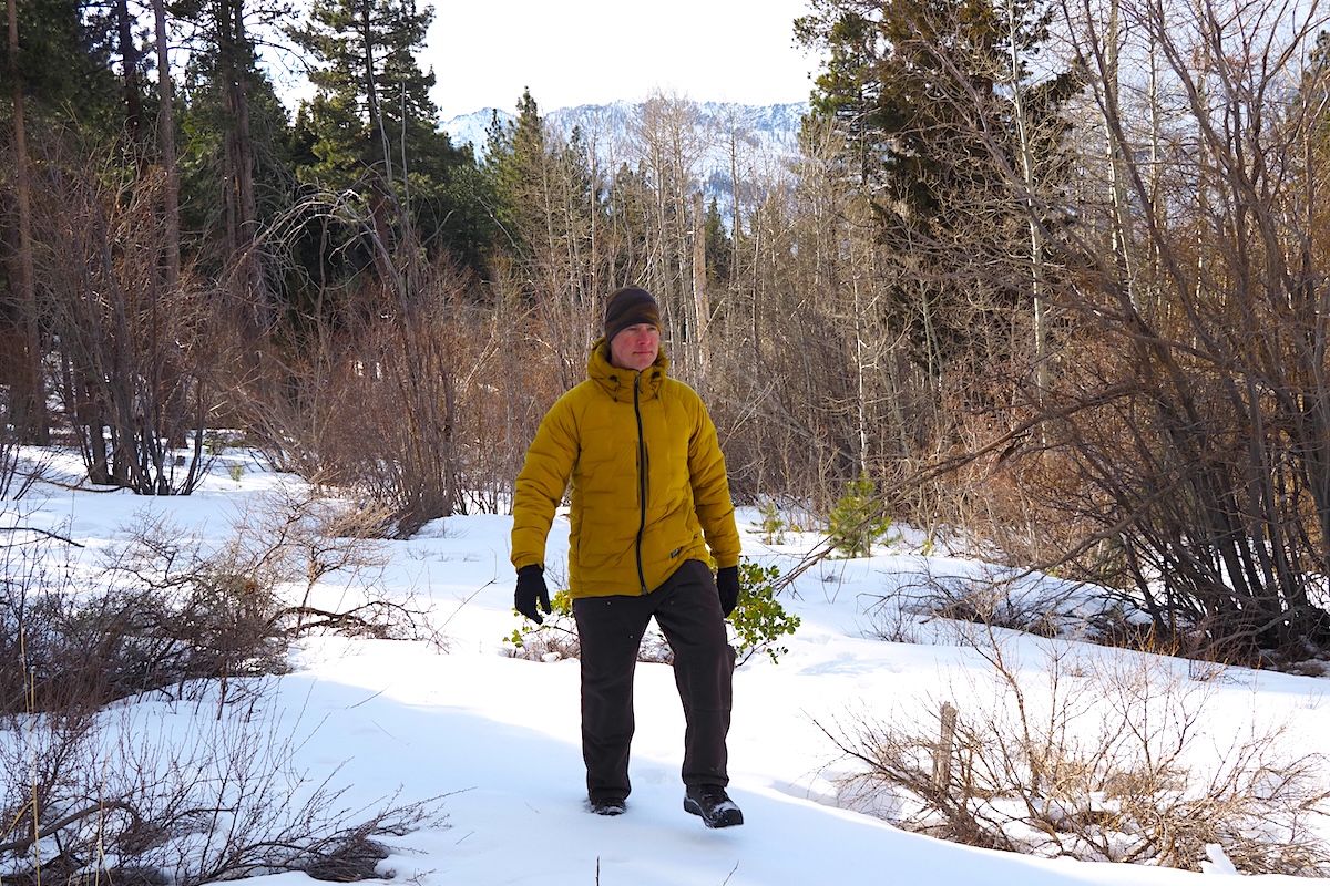 A man wearing the Stretchdown Parka and walking in the woods