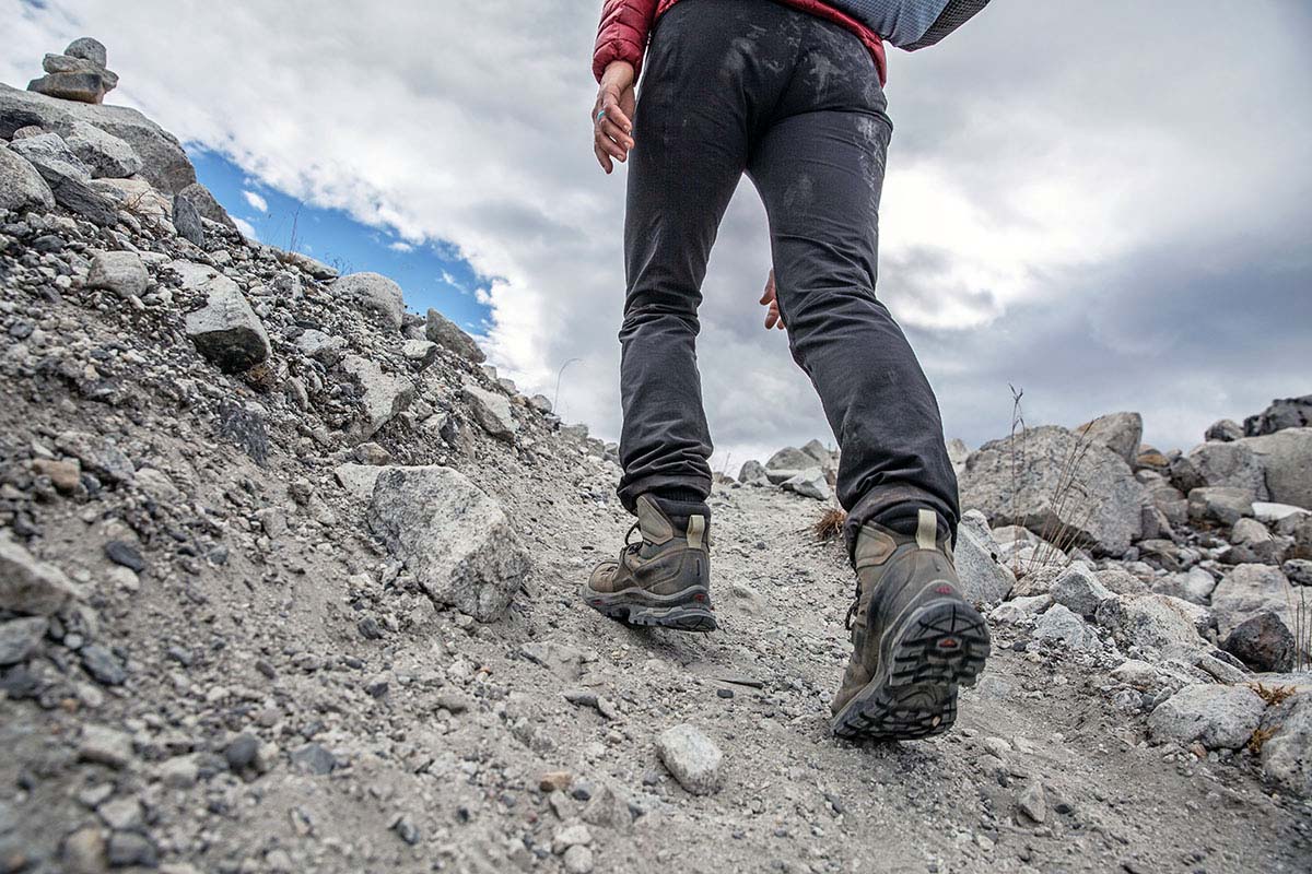 A woman hikes up a rocky trail in the mountains.