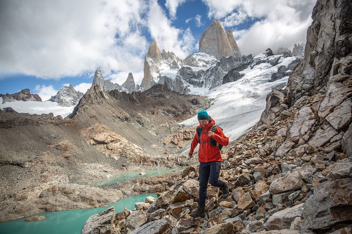 The sea-green lake water and glaciered slopes of Cerro Torre rise behind a hiker in Patagonia.