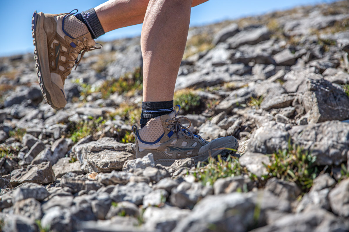 A pair of hiking boots walking over rocky ground