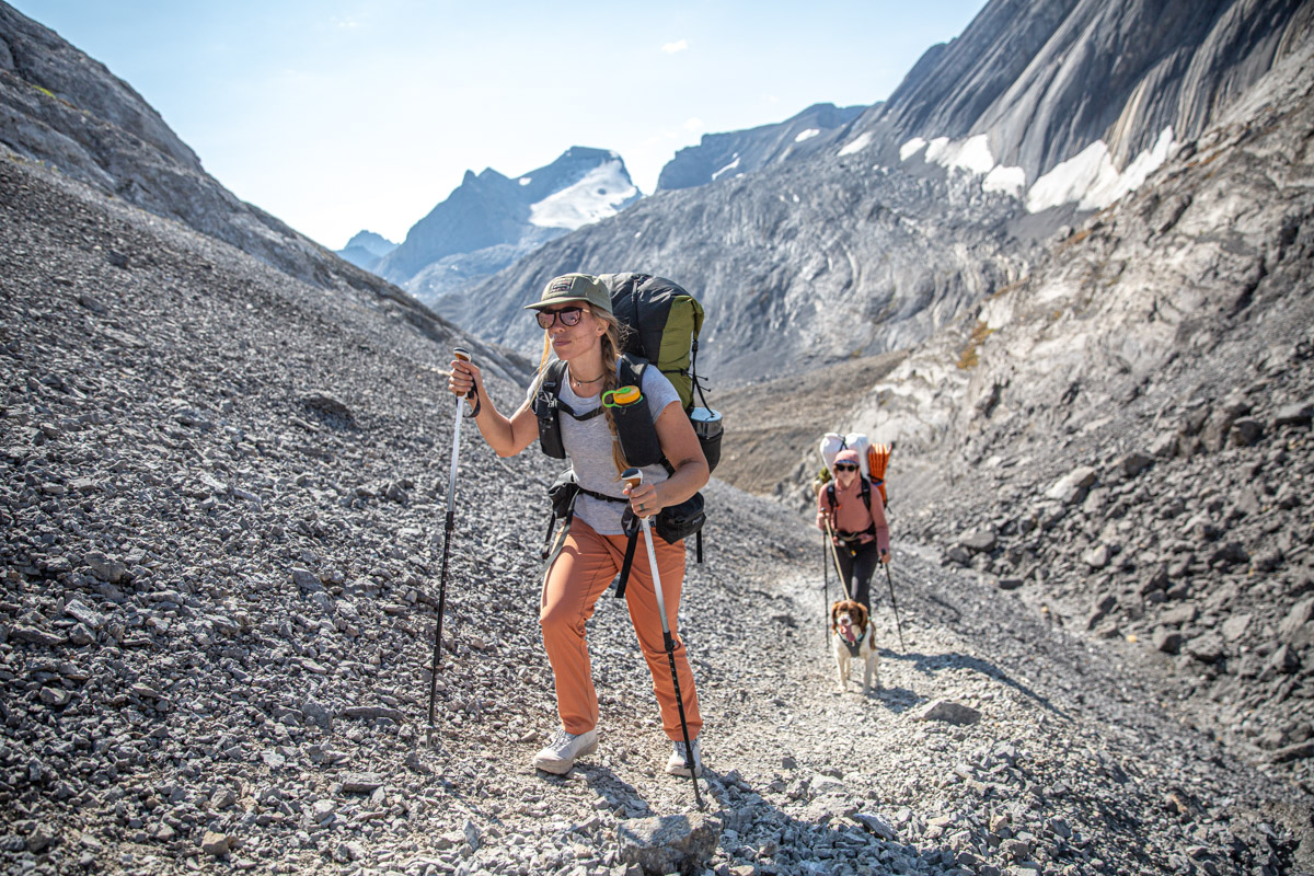 Two women backpack up a talus-filled mountain valley.