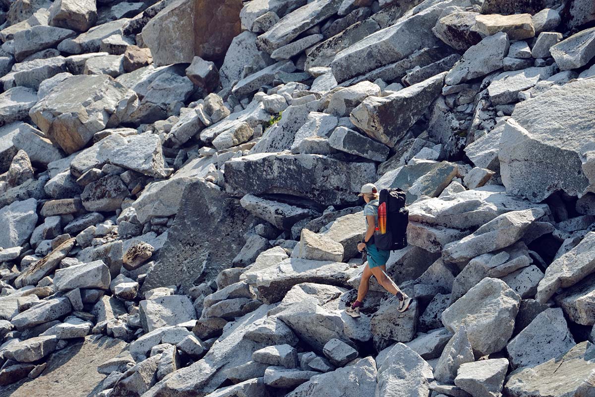 Hiking through boulder field, a woman is shown from the side