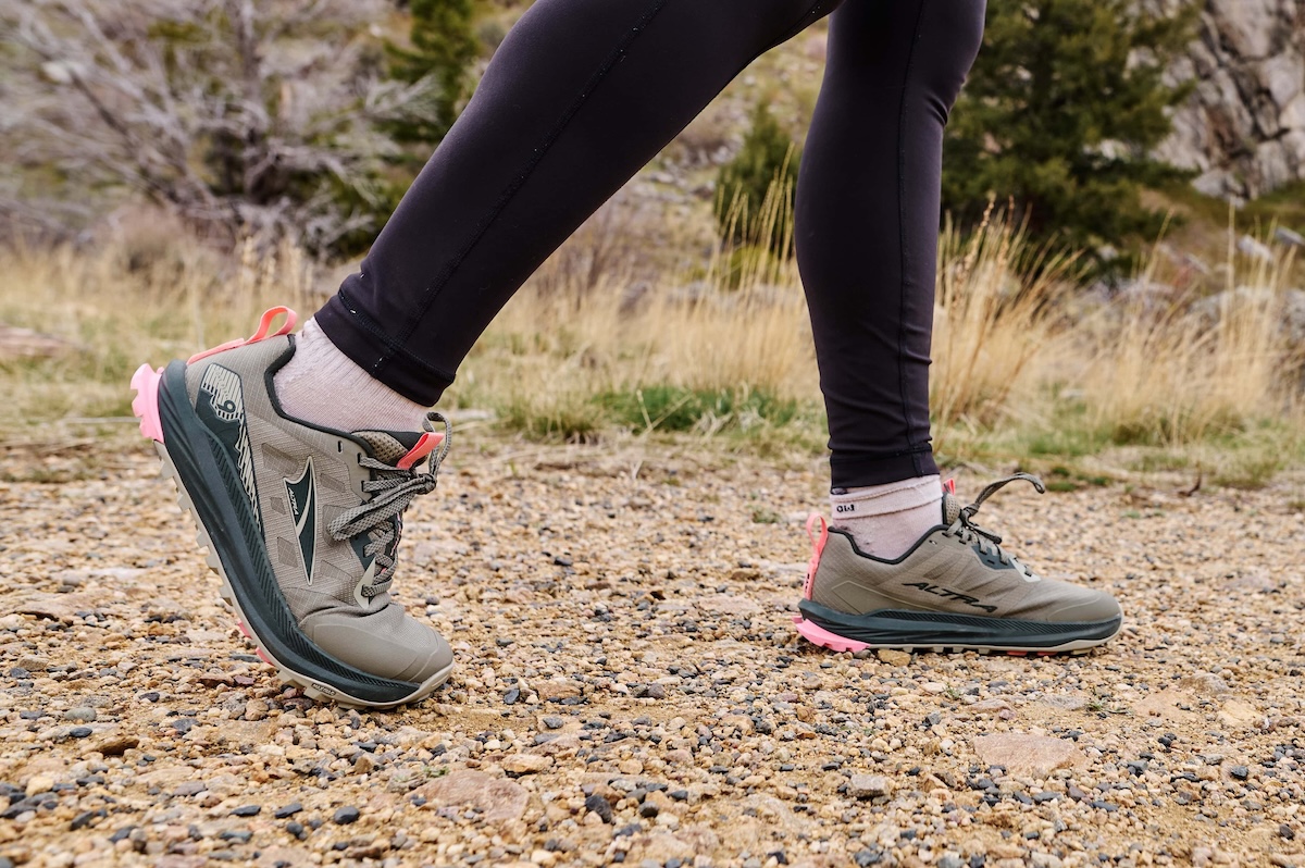 A woman walks along a sandy trail in a pair of altra lone peak 9 shoes