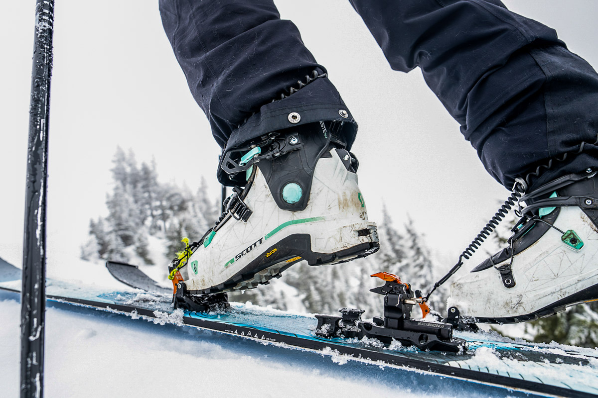 A pair of white women's ski boots walking on tech bindings