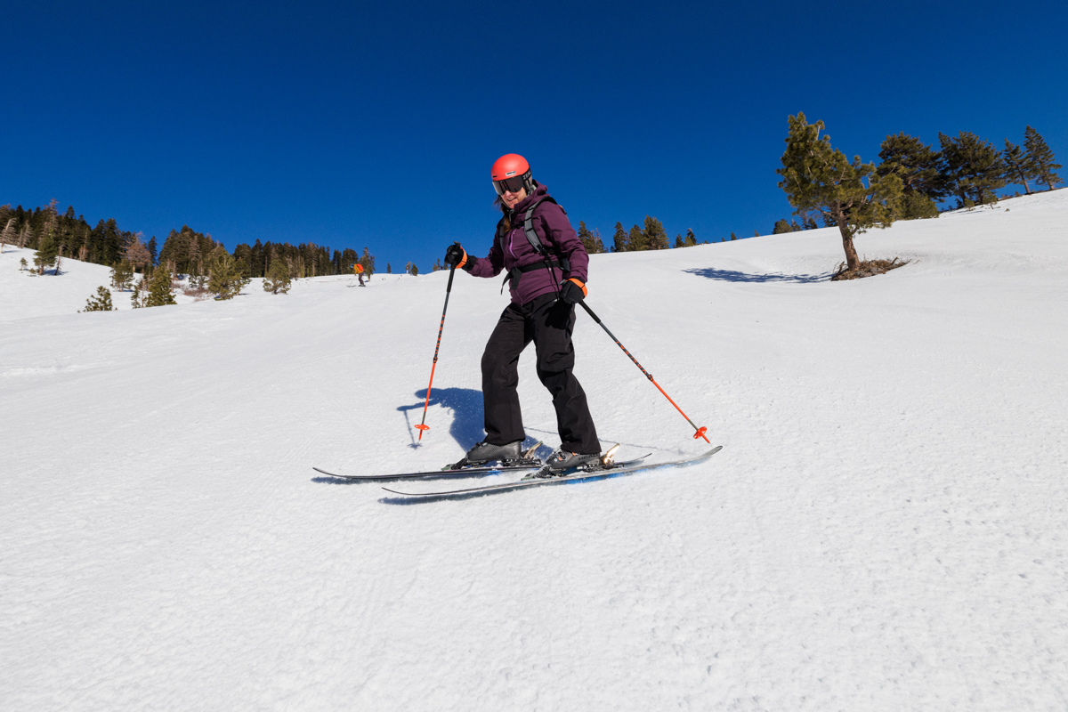 A woman skiing down a snowy hill wearing black ski pants