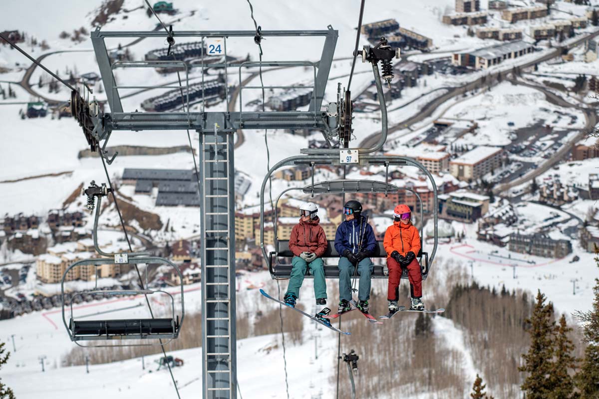 Three skiers ride a chairlift above Crested Butte resort in Colorado