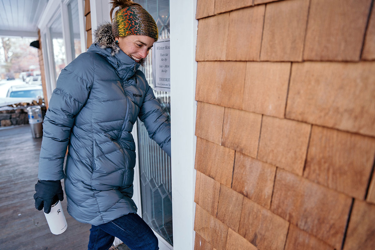 A smiling woman walks through a shop door