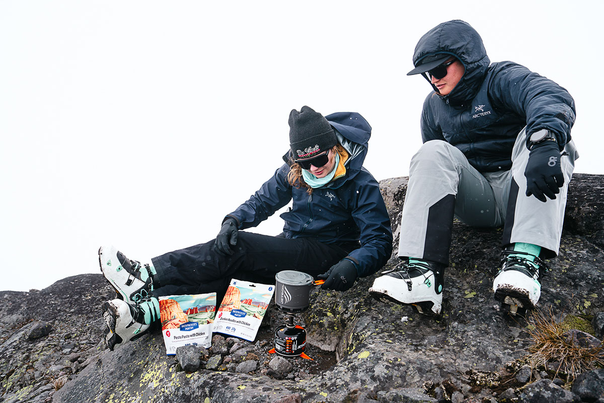 Two women sitting on a rock with a backpacking stove