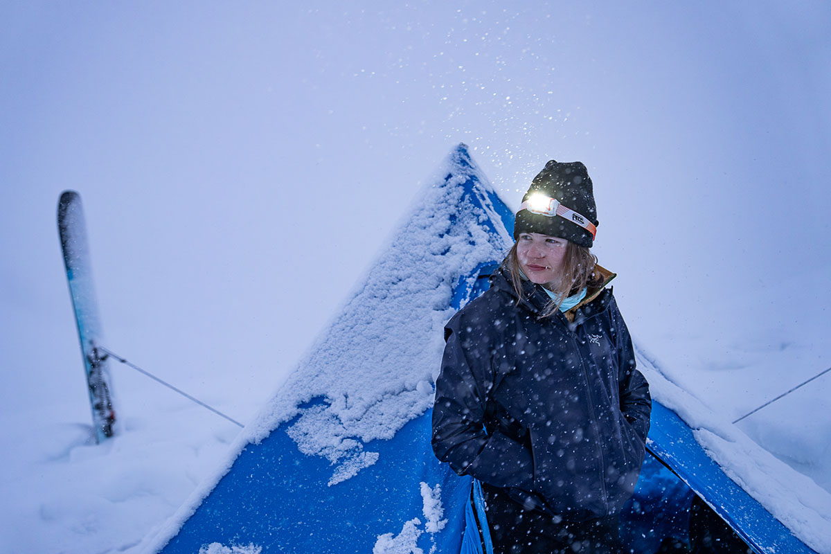 A woman standing outside of a tent in a snow storm