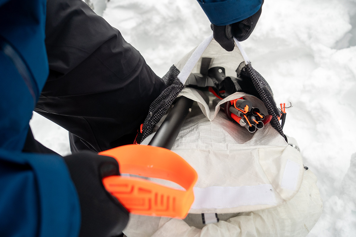 Putting a shovel in a avalanche gear pocket in a backpack