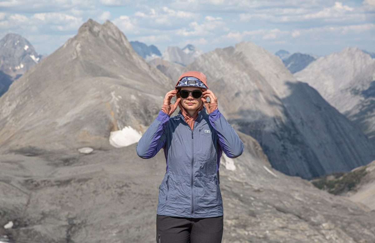 A woman adjusting her sunglasses and wearing a wind jacket