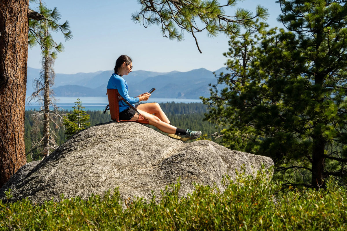 A woman sitting on a rock in a backpacking chair