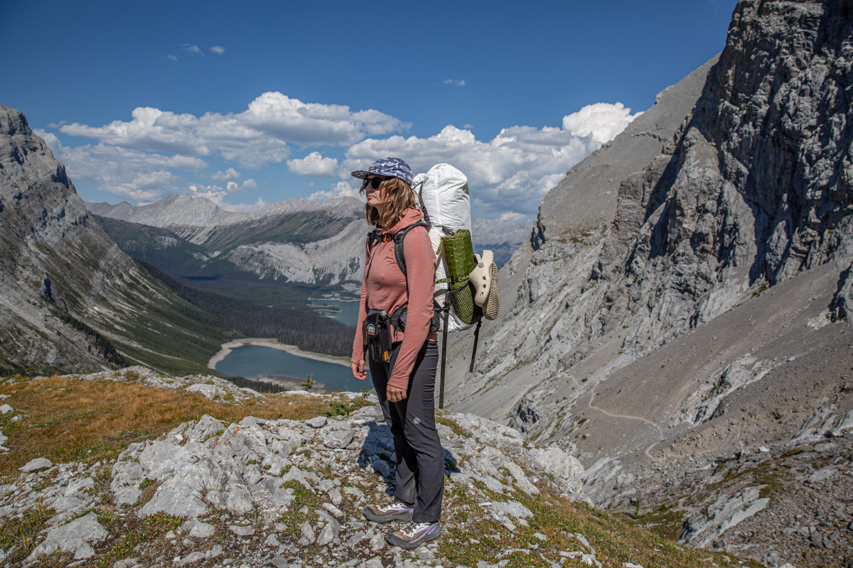 A woman standing on a trail wearing black hiking pants.