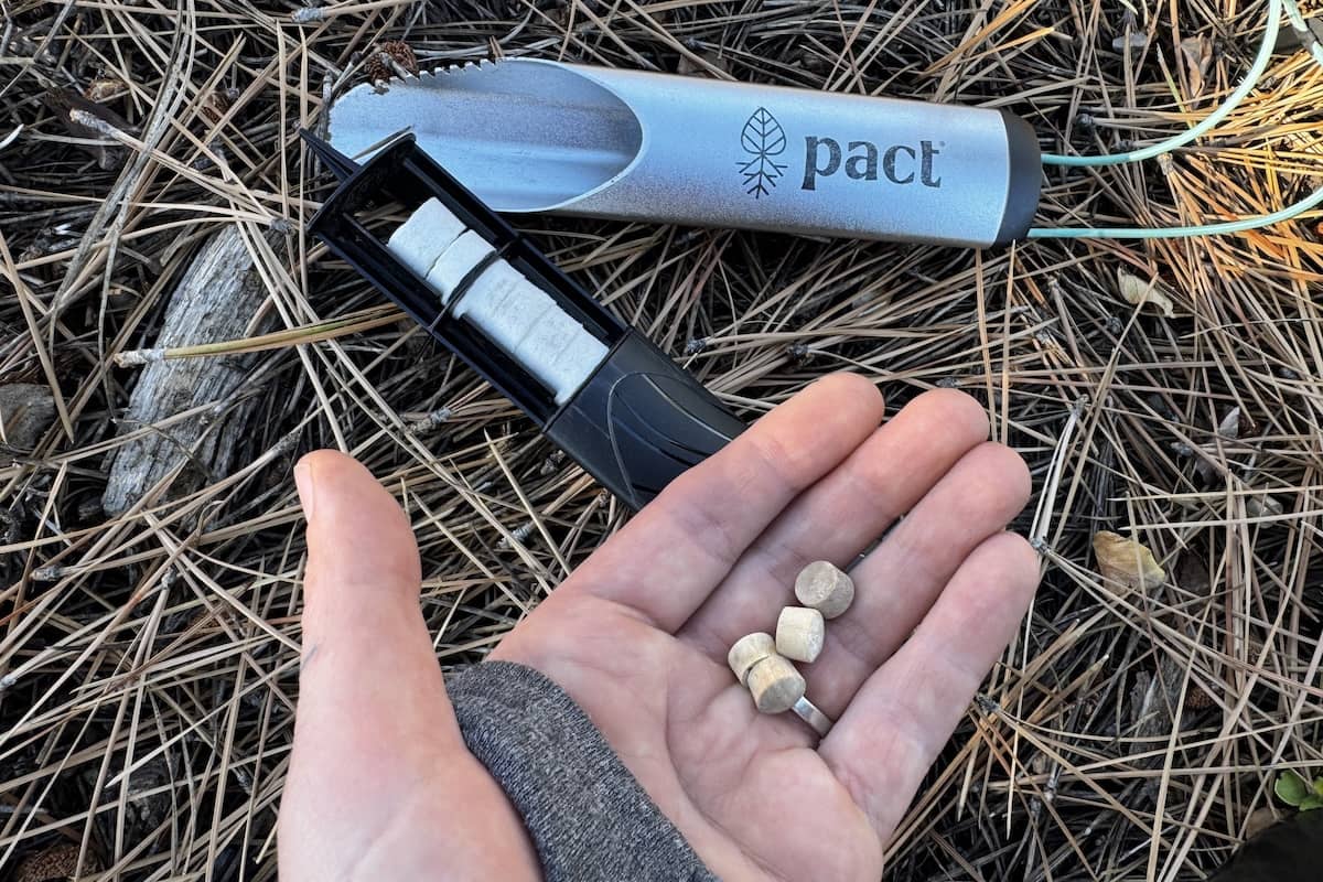 A hand hold out mycelium tabs from the Pact Bathroom kit